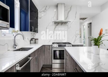 Una bella cucina con una grande isola blu con sgabelli da bar, luci a  sospensione nere, cappa di stufa di design, e armadi bianchi Foto stock -  Alamy