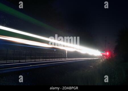 Bartlett, Illinois, Stati Uniti. Lungo l'esposizione cattura i fari che si stagliano da un treno per pendolari Metra che illumina la notte. Foto Stock