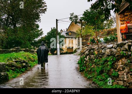 Pellegrino che arriva a la Faba in una giornata autunnale di pioggia. Modo francese, modo di San Giacomo. La Faba, Vega de Valcarce, León, Castiglia e Leon, Spagna, Europa Foto Stock