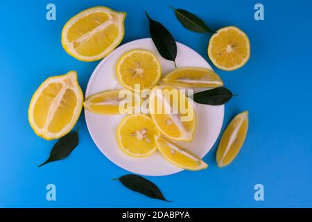 Tagliate a fette ​​lemons su un piatto bianco su sfondo azzurro. Vista dall'alto. Foto Stock