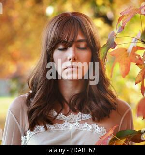 Bella giovane donna con gli occhi chiusi. Ritratto d'autunno Foto Stock