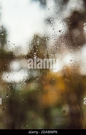 Riflesso offuscato della strada in una finestra appannata, gocce d'acqua dopo la pioggia scorrono sul vetro. Gocce d'acqua sulla finestra. Concetto di umore piovoso. Foto Stock