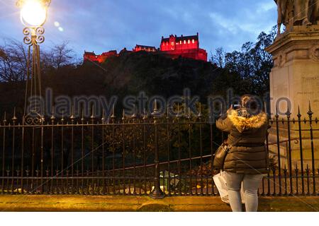 Edimburgo, Scozia, Regno Unito. 11 Nov 2020. Il visitatore scatta una fotografia del Castello di Edimburgo ancora illuminato in Remembrance rosso papavero contro il cielo blu al tramonto. Credit: Craig Brown/Alamy Live News Foto Stock