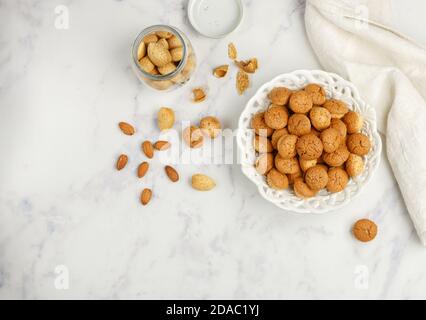 Amaretti-biscotti tradizionali italiani alle mandorle in un piatto bianco su uno sfondo vista dall'alto in marmo. Biscotti Amarettini. Messa a fuoco selettiva, spazio di copia Foto Stock
