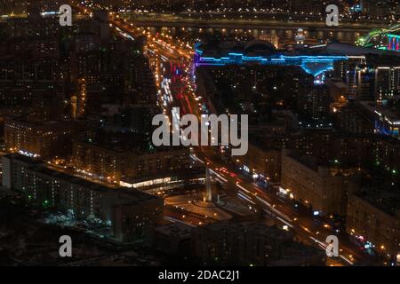 Vista aerea del drone sulla via della città di Mosca, con il traffico delle auto in rapido movimento e il percorso dei semafori. Illuminazione calda di notte. Ora di punta, urbano, trasporto Foto Stock