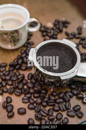 Un portafiltro per macchina da caffè e una tazza in porcellana chicchi di caffè Foto Stock