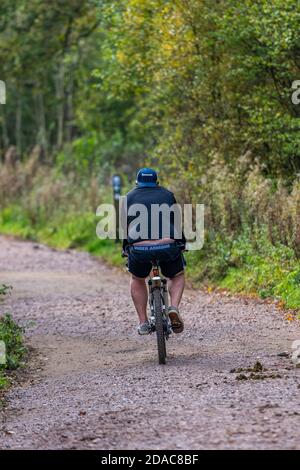 un uomo obese in bicicletta che attraversa il bosco in bicicletta nel bosco per perdere peso e per fare qualche esercizio. Foto Stock