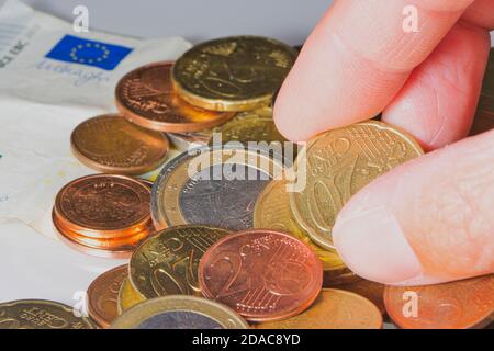 primo piano di dita che sottraevano centesimi di euro a uno stack di monete Foto Stock