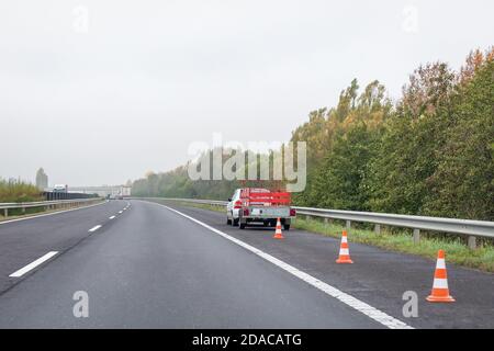 Auto difettosa con rimorchio rosso e coni stradali sulla corsia di arresto di emergenza sul lato della strada. Problema con il veicolo in autostrada Foto Stock