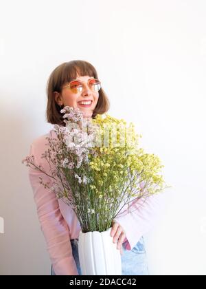 Giovane donna in camicia rosa con vaso di fiori Foto Stock