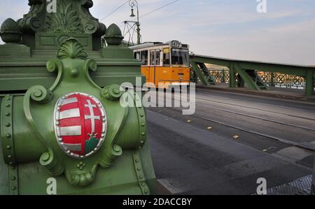 Liberty Bridge Coat of Arms dettaglio e tram sullo sfondo, Budapest, Ungheria Foto Stock