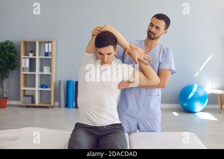 Chiropractor o fisioterapista che esamina il braccio del giovane uomo per aiutarlo curare i problemi di salute Foto Stock