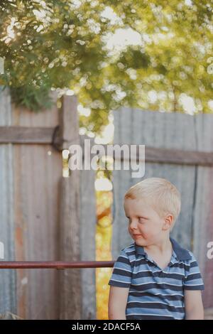 Scatto verticale di un bambino biondo che indossa una t-shirt a righe e in posa Foto Stock