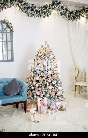 Biglietto d'auguri per il nuovo anno. Interni eleganti con alberi di Natale ricoperti di neve e alla moda con scatole di regali, decorati con ghirlande, corone, vetro Foto Stock