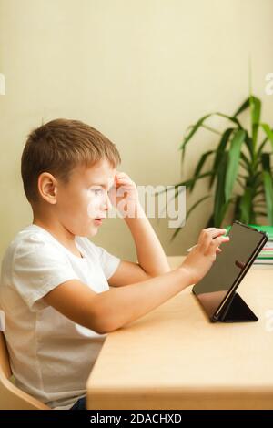 Figlio che utilizza i gadget per lo studio. Concetto di istruzione e formazione a distanza. Homeschooling durante la quarantena. Intrattenimento domestico. Foto Stock