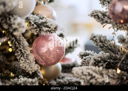 Biglietto d'auguri per il nuovo anno. Palline di vetro giocattolo, fiocchi di neve sullo sfondo di un albero di Natale sfocato con ghirlande di luci bokeh. Vacanza luminosa. Neve Foto Stock