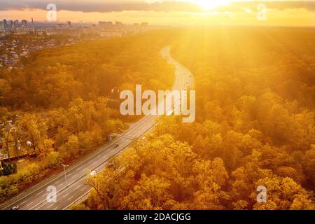 Vista della strada autostradale attraverso la foresta rossa d'autunno dall'alto, concetto di avventura di viaggio Foto Stock