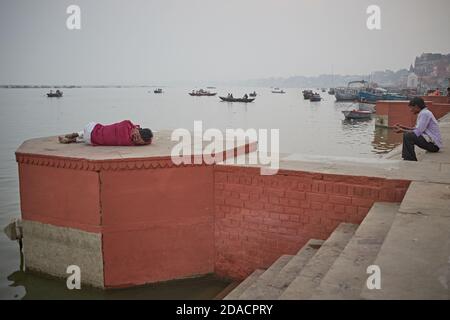 Varanasi, India, novembre 2015. Un uomo dorme in un ghat sul fiume Gange. Foto Stock