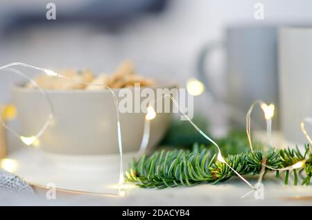 Su un vassoio di marmo con bordo dorato, ci sono due tazze grigie di tè e un biscotto di pan di zenzero di cioccolato. Un regalo per Babbo Natale. Albero di Natale ramo Foto Stock
