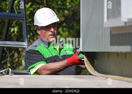 GREYMOUTH, NUOVA ZELANDA, 21 OTTOBRE 2020: Un operatore di gru lavora per sollevare un piccolo edificio da un camion sui suoi pali. Foto Stock