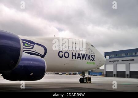 Il parcheggio della squadra di football dei Seahawks Boeing 747-8 Freighter si trova di fronte all'edificio del Dreamlifter Operations Center all'aeroporto di Plainfield, Everett, Washington Foto Stock