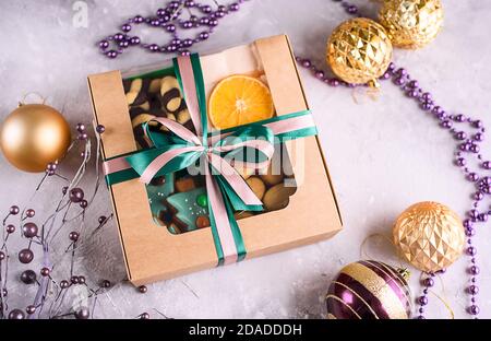 Scatola con nastri in raso e deliziose prelibatezze per Capodanno e Natale. Dessert di Capodanno su sfondo chiaro. buon natale Foto Stock
