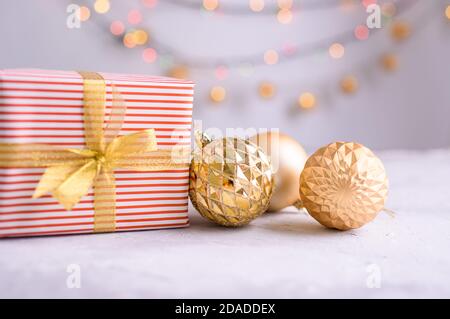 Il contenuto di Capodanno con ciuffi ATE, giocattoli d'oro per l'albero di Natale. Regalo decorato con nastro d'oro, il simbolo del nuovo anno 2021. Foto Stock