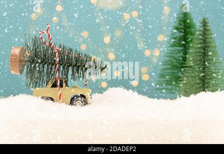 Biglietto di Natale o Capodanno con auto giocattolo e miniatura dell'albero di natale e luci bokeh di Natale sullo sfondo. Foto Stock