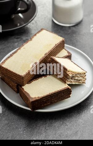 Biscotti croccanti di cialda ripieni di crema di cioccolato su tavola nera. Foto Stock