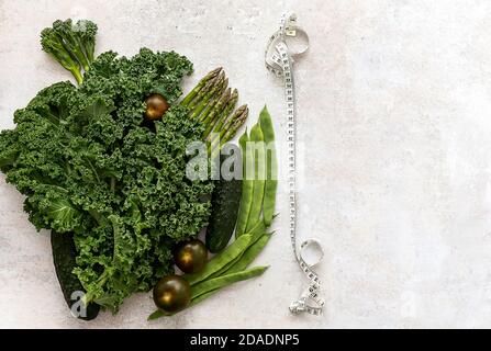 Dieta e sfondo sano con verdure verdi e metro nastro. Foto Stock