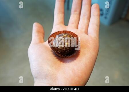 Primo piano tenendo la mano No cuocere cioccolato cacao proteine energia sfera di potenza Foto Stock