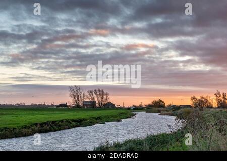 Willingham Cambridgeshire, Regno Unito. 12 Nov 2020. Un inizio nuvoloso all'alba nel Cambridgeshire Fens da una stazione di pompaggio di drenaggio sul fiume Old West. Dopo una notte di pioggia, si prevede una giornata di sole. Credit: Julian Eales/Alamy Live News Foto Stock