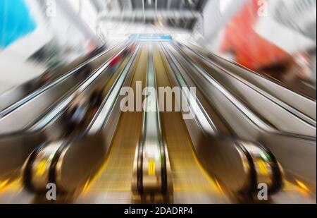 Persone su scale mobili nel business center. Immagine con sfocatura del movimento Foto Stock