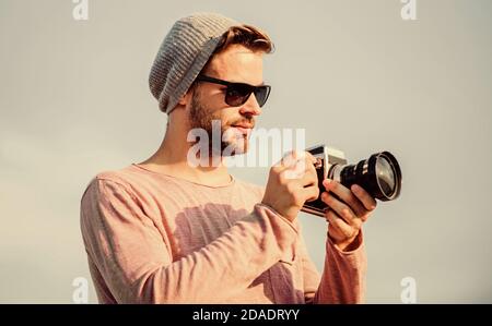 Fotografo professionista. Bel fotografo macchina fotografica retro. Concetto di fotogiornalista. Guy fotografo all'aperto cielo sfondo. Hipster reporter scattare foto. Impostazioni manuali. Blogger da viaggio. Foto Stock