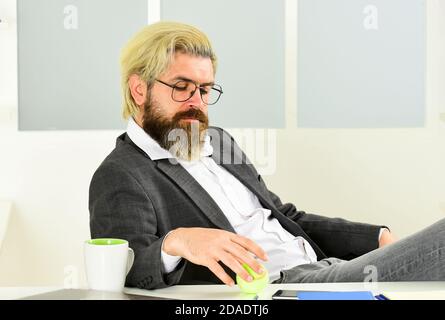 Business manager rilassante. Lavoro in ufficio. Concetto aziendale. Hipster giocare a tennis palla. Burnout e mancanza di idee. Concetto di crisi. Uomo imprenditore di successo formale abito da lavoro seduta interni ufficio. Foto Stock