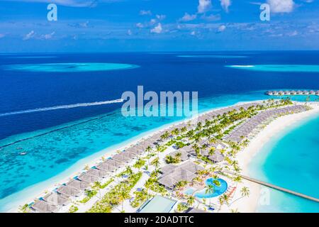 Vista aerea di un'isola tropicale in acque turchesi. Lussuose ville sull'acqua in un resort tropicale sull'isola. Maldive vacanza paesaggio aereo vacanza Foto Stock