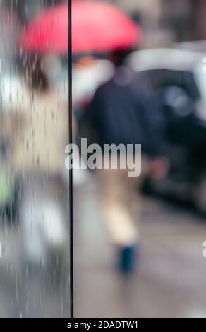 Pioggia in città. Scena offuscata della vita urbana. Sfondo astratto emotivo con persone sfocate sulle strade di New York in una giornata piovosa Foto Stock