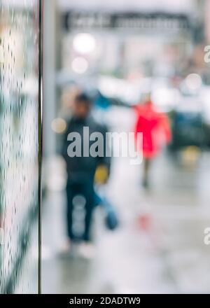 Pioggia in città. Scena offuscata della vita urbana. Sfondo astratto emotivo con persone sfocate sulle strade di New York in una giornata piovosa Foto Stock