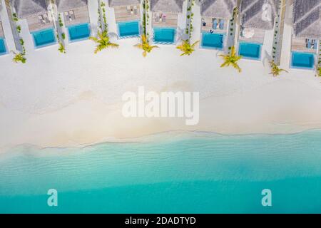 Atolli e isole nelle Maldive. Isola tropicale alle Maldive con ville d'acqua di lusso, bungalow su mare blu incredibile. Vacanza estiva, vista aerea Foto Stock