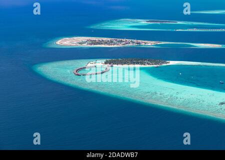 Vista aerea di un'isola tropicale in acque turchesi. Lussuose ville sull'acqua in un resort tropicale sull'isola. Maldive vacanza paesaggio aereo vacanza Foto Stock