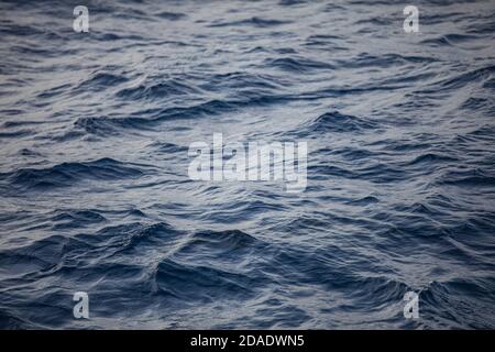 Superficie blu del mare con onde luminose. Trama di fondo di un oceano azzurro calmo e profondo con increspature sulla superficie dell'acqua di mare Foto Stock