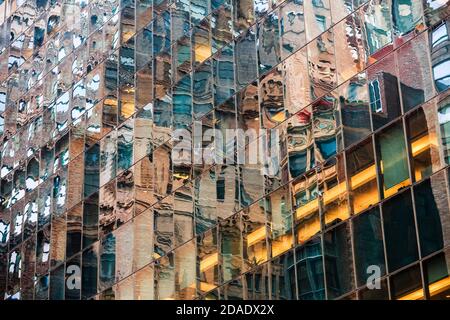 Astratto sfondo di NYC. Facciata in vetro di un grattacielo a New York City con riflessi speculari di case e strade di Manhattan Foto Stock