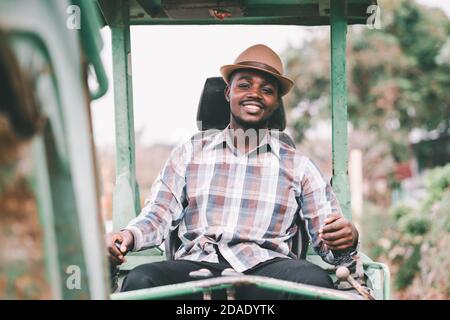 Smile operaio africano di sesso maschile che opera escavatore sul cantiere Foto Stock