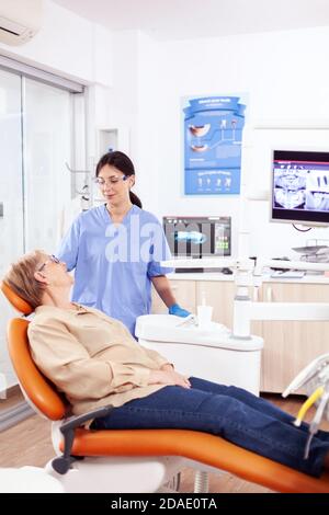 Assistente in clinica odontoiatrica che interroga pazienti anziani sui problemi dentali. Donna anziana che parla con l'infermiera medica in ufficio di stomatologia circa il problema dei denti. Foto Stock