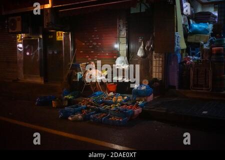 Un venditore di frutta e verdura si addormentò di fronte al suo negozio. Foto Stock