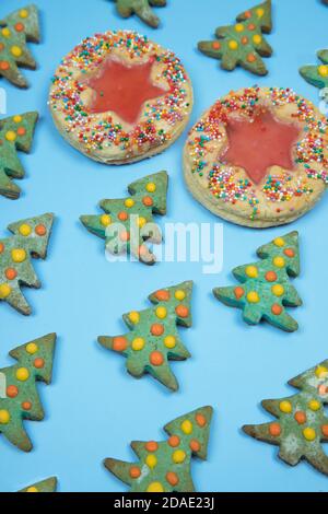 Biscotti fatti in casa di Natale disposti in fila in un modello su uno sfondo blu orientamento verticale. Foto Stock