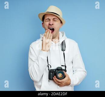 L'uomo con la macchina fotografica è stanco e sbadiglia Foto Stock