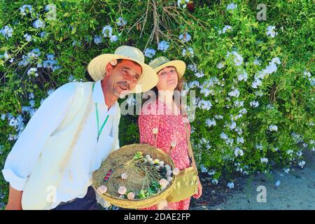 Un venditore di fiori di strada offre Jasmine a una giovane donna in Sidi Bou ha detto. Un mercante arabo e una ragazza contro un albero di gelsomino - Sidi Bou ha detto, Tunisia, Foto Stock