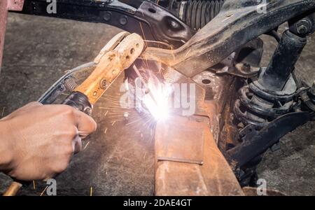 Saldatore saldatura metallo o acciaio di costruzione di telaio di automobile In garage Foto Stock