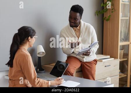Due partner commerciali che discutono di lavoro tra loro durante il lavoro in squadra in ufficio Foto Stock